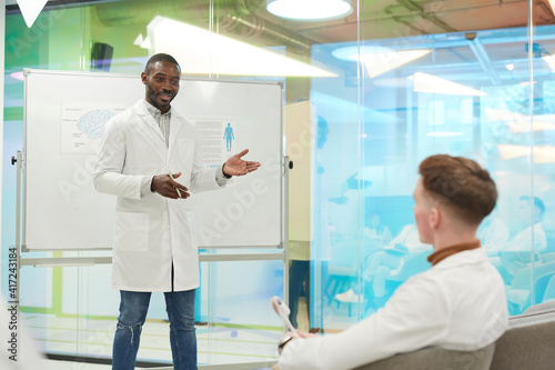 Portrait of African-American man standing by whiteboard while giving presentation during medical seminar in college  copy space