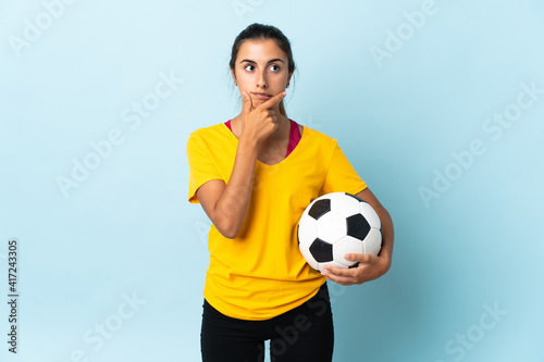 Young hispanic football player woman over isolated on blue background having doubts and thinking © luismolinero