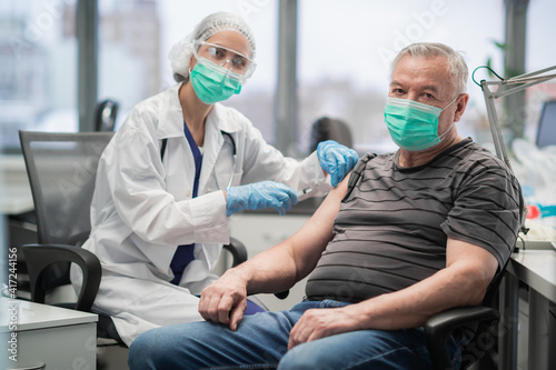 An elderly man receives a vaccination against the covid 19 coronavirus at the clinic. Universal vaccination of the population.