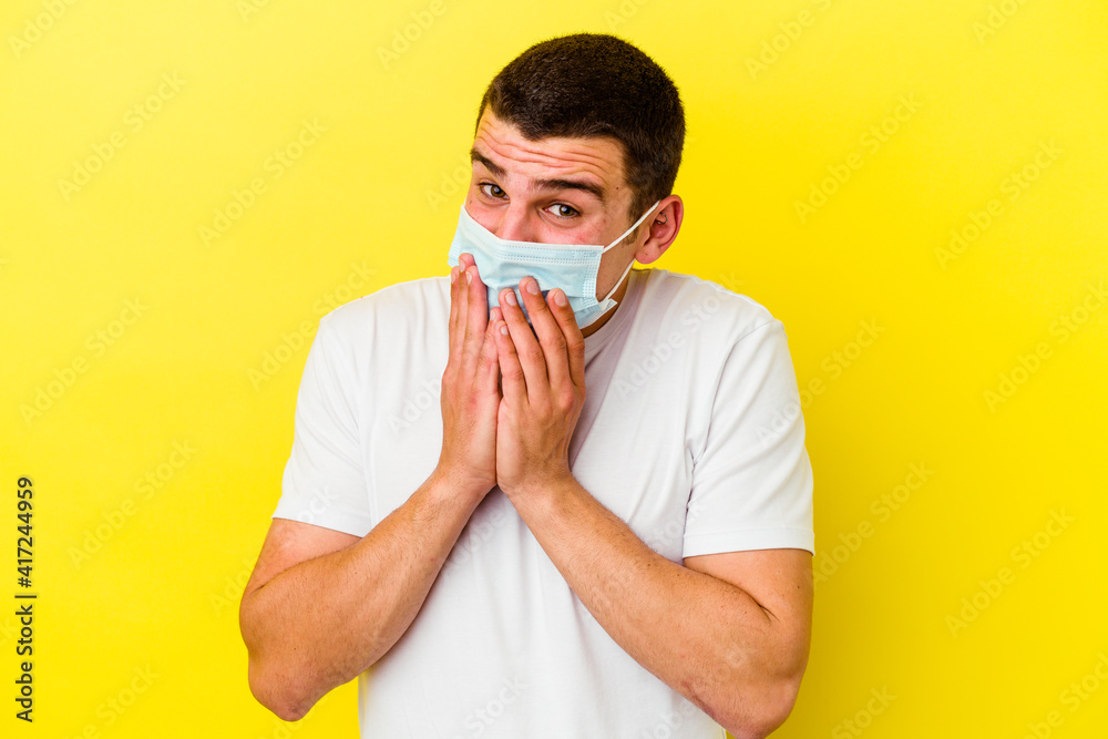 Young caucasian man wearing a protection for coronavirus isolated on yellow background biting fingernails, nervous and very anxious. Young caucasian man wearing a protection for coronavirus isolated on yellow background biting fingernails, nervous and very anxious.