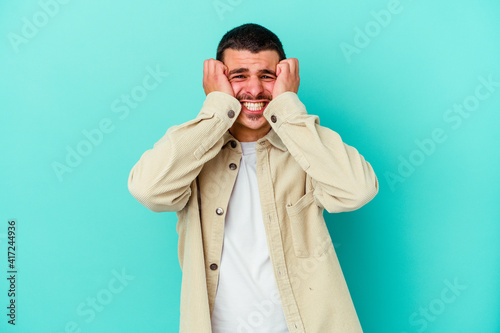 Young caucasian man isolated on blue background crying, unhappy with something, agony and confusion concept.