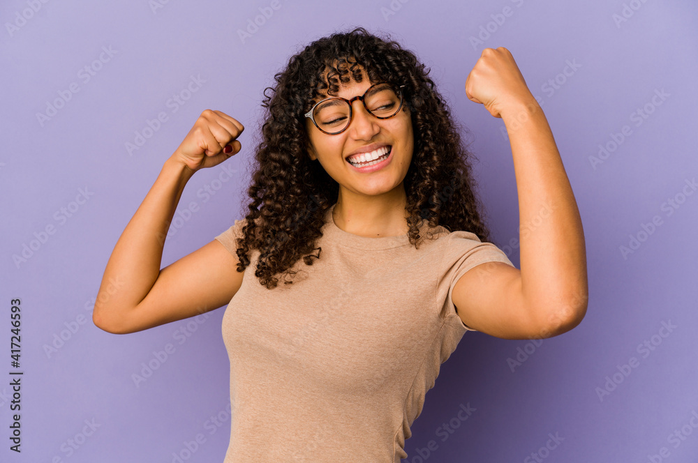Young african american afro woman isolated raising fist after a victory, winner concept. Young african american afro woman isolated raising fist after a victory, winner concept.