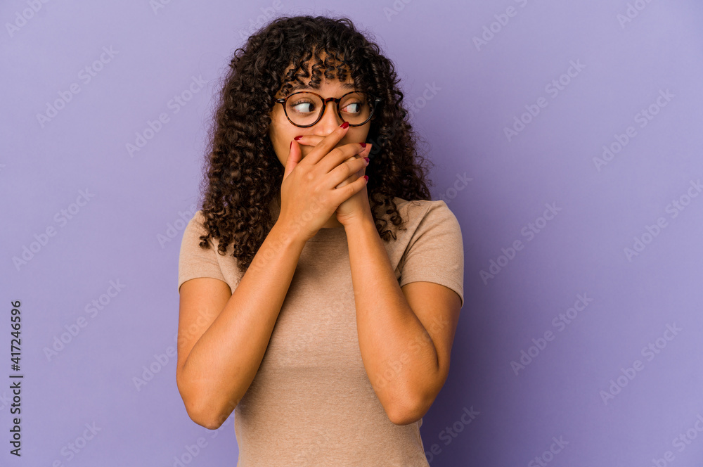 Young african american afro woman isolated thoughtful looking to a copy space covering mouth with hand.