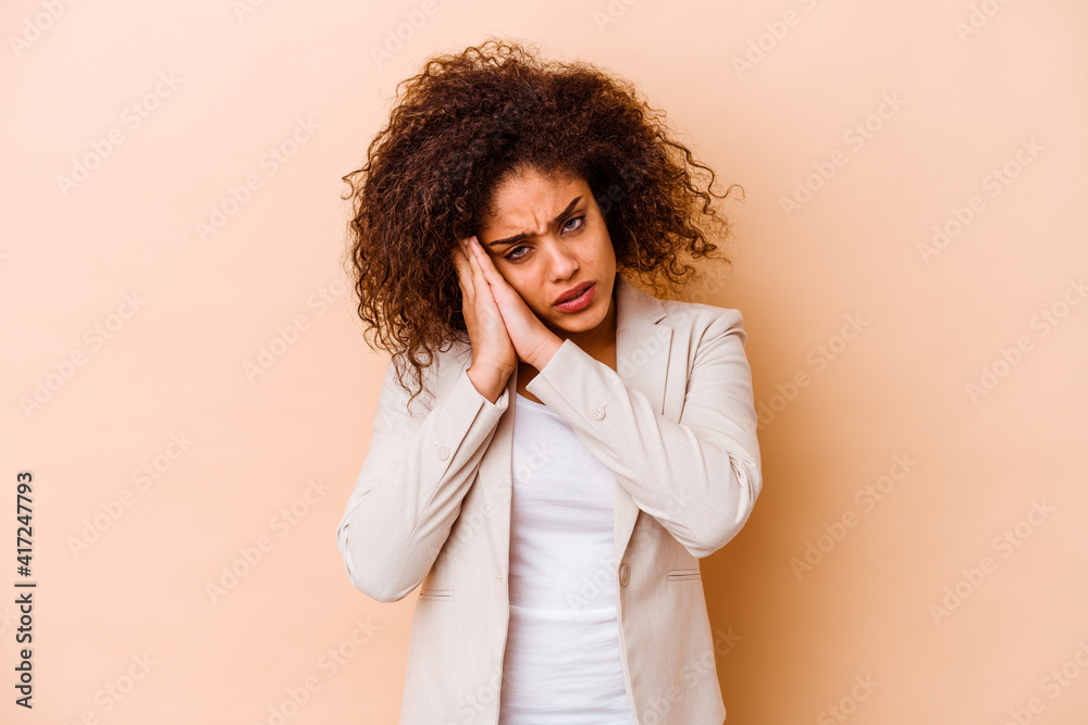 Young african american woman isolated on beige background yawning showing a tired gesture covering mouth with hand. Young african american woman isolated on beige background yawning showing a tired gesture covering mouth with hand.