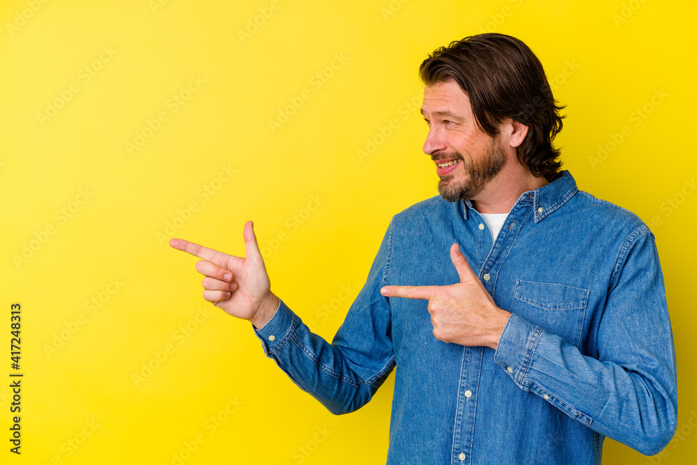 Middle age caucasian man isolated on yellow background excited pointing with forefingers away. Middle age caucasian man isolated on yellow background excited pointing with forefingers away.