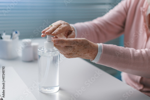 Tablou pe pânză Senior woman applying sanitizer on her hands