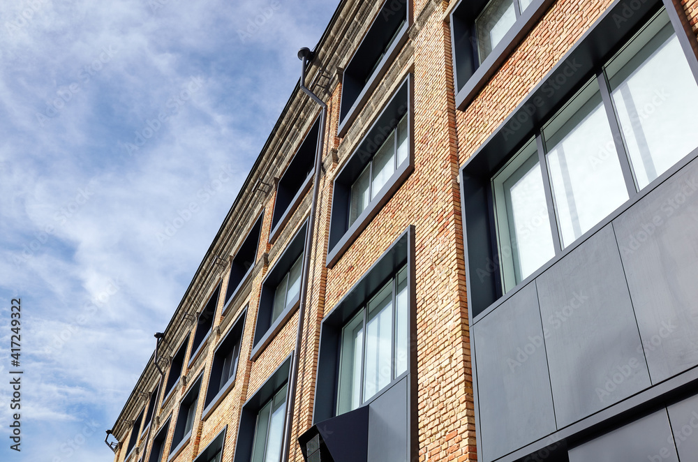 Brick building with windows and downspout against blue sky