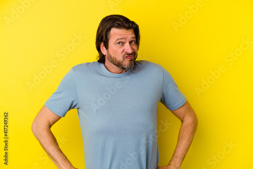 Middle age caucasian man isolated on yellow background frowning face in displeasure, keeps arms folded.