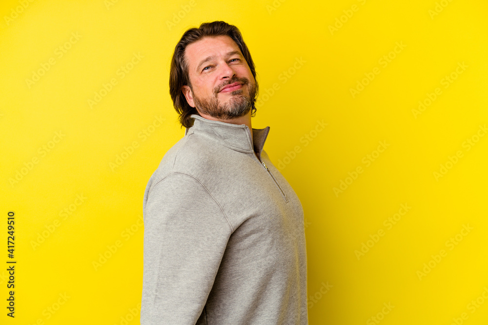 Middle age caucasian man isolated on yellow background confident keeping hands on hips.