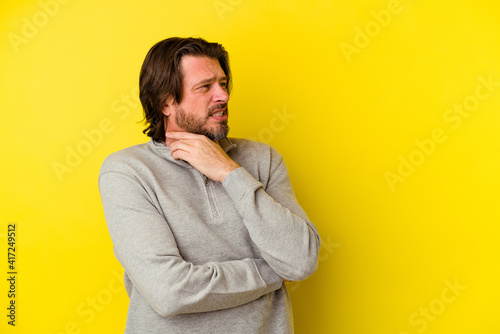 Middle age caucasian man isolated on yellow background suffers pain in throat due a virus or infection. © Asier