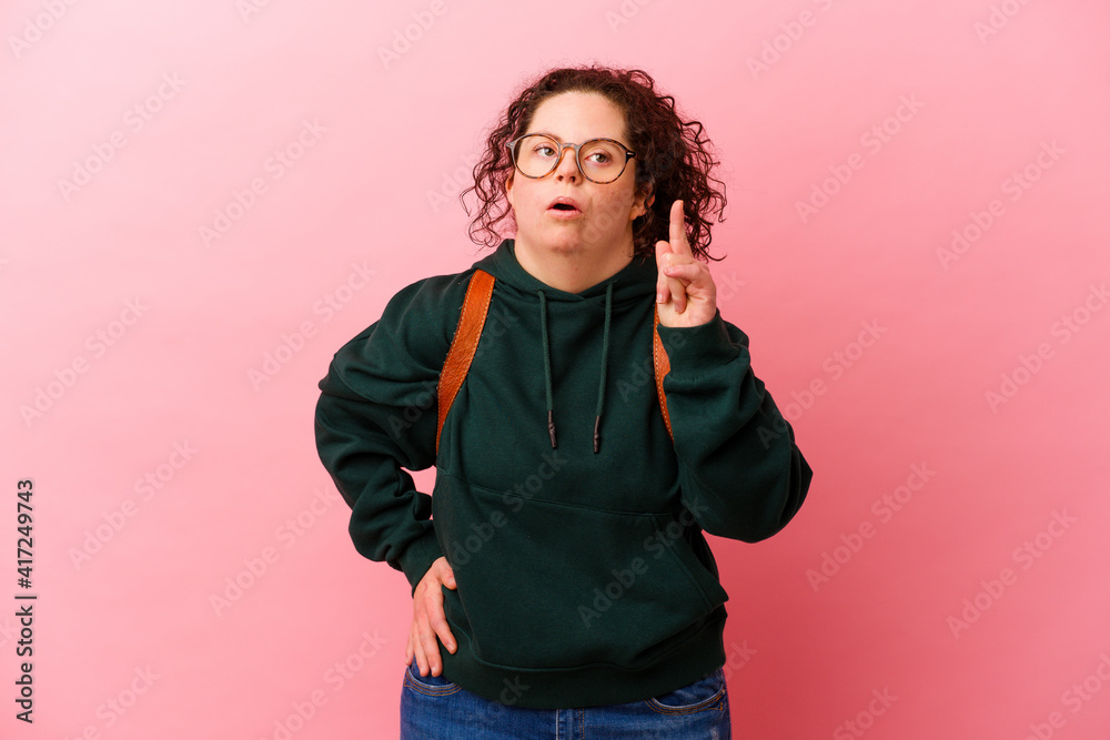 Young student woman with Down syndrome isolated on pink background having an idea, inspiration concept.