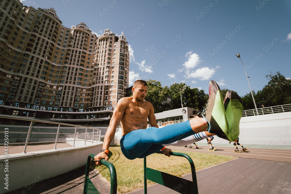 Fototapeta premium Strong man doing exercises on uneven bars in outdoor street gym.