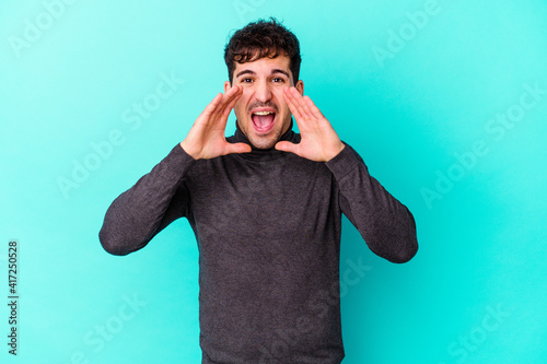 Young caucasian man isolated on blue background shouting excited to front.