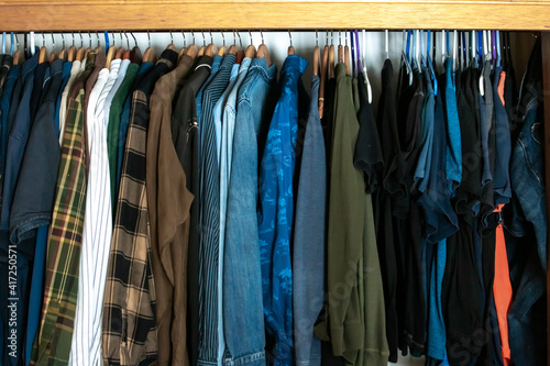 A closet filled with long sleeved shirts and flannels hanging from a cedar beam in London, Ontario, Canada, 2021.