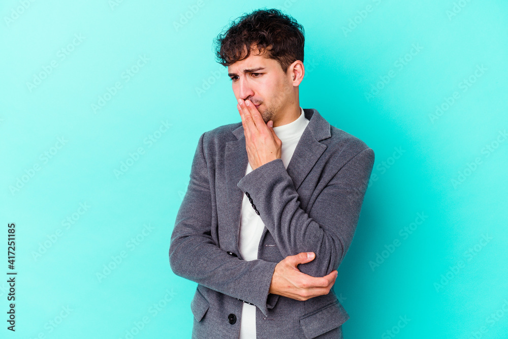 Young caucasian man isolated on blue background yawning showing a tired gesture covering mouth with hand. Young caucasian man isolated on blue background yawning showing a tired gesture covering mouth with hand.