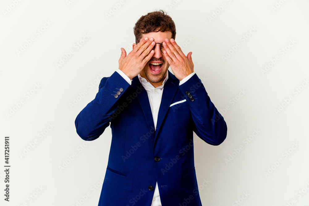 Young business caucasian man isolated on white background covers eyes with hands, smiles broadly waiting for a surprise. Young business caucasian man isolated on white background covers eyes with hands, smiles broadly waiting for a surprise.