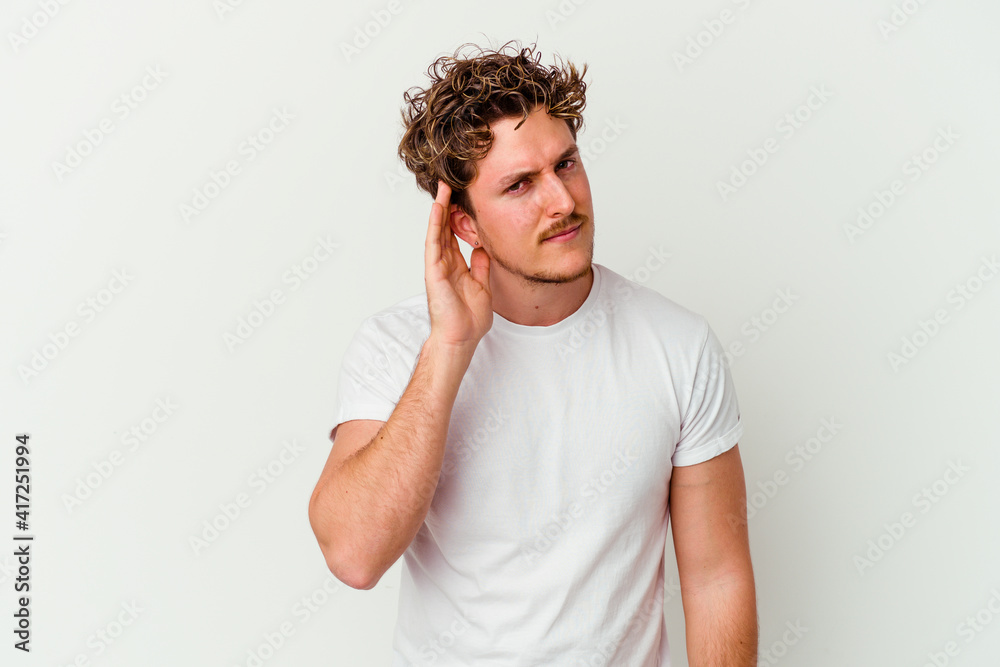 Young caucasian man isolated on white background trying to listening a gossip. Young caucasian man isolated on white background trying to listening a gossip.