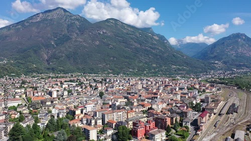 General view of Domodossola city at foot of green Italian Alps in sunny summer day looking out over railway station, Piedmont