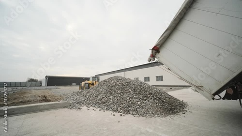 A truck dumps rubble onto a construction site. Clearing site