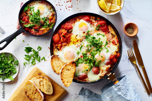 Top view breakfast Shakshuka with vegetables, herbs, tomato sauce and grilled bread slices photo