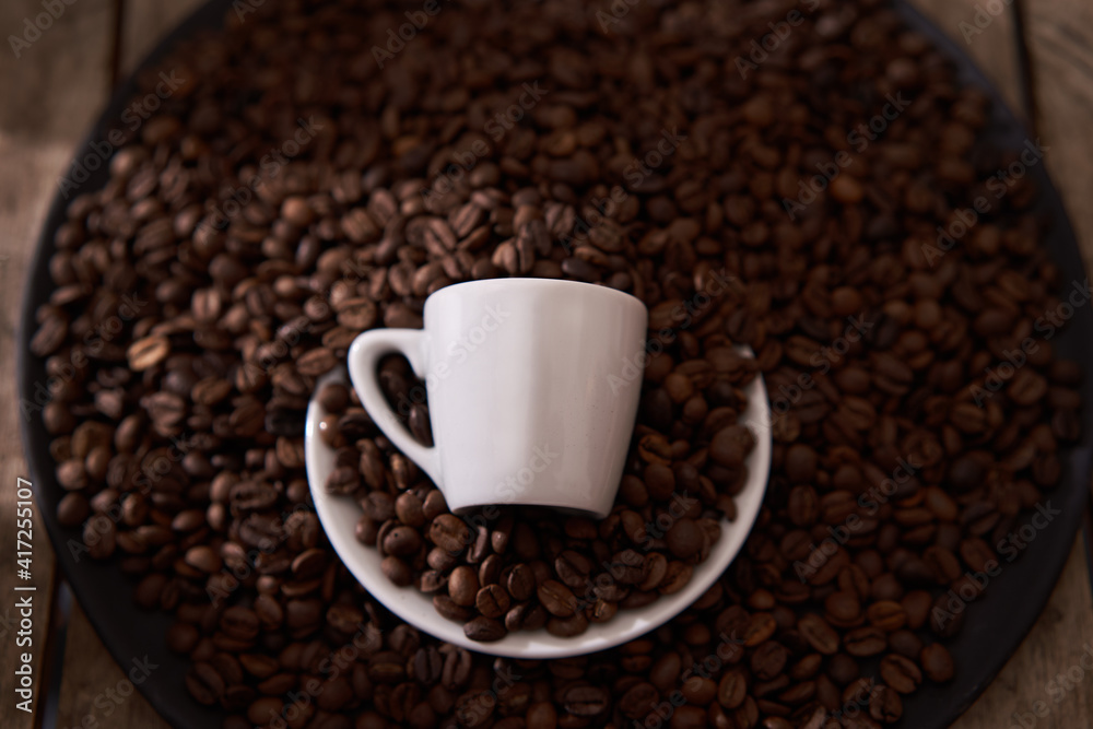 top view, white coffee cup, raw and roasted coffee beans in the dark plate on the wooden table top view, white coffee cup, raw and roasted coffee beans in the dark plate on the wooden table