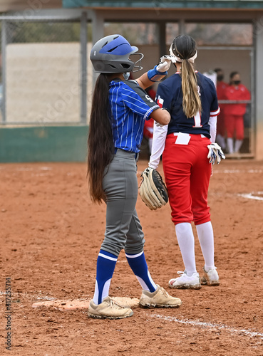 Girl with very long brown hair playing softball in a game