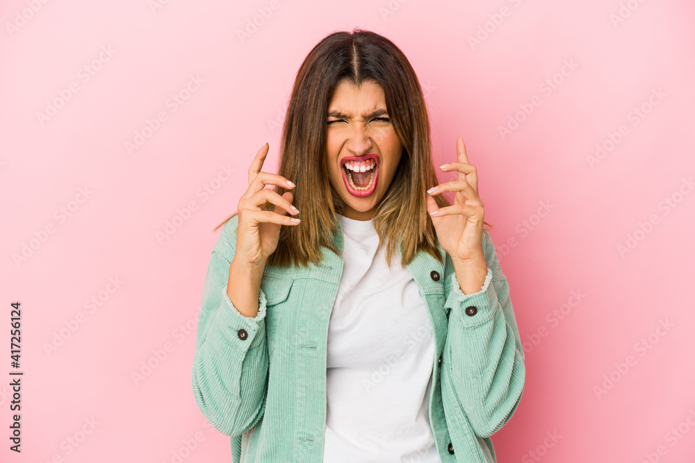 Young indian woman isolated on pink background upset screaming with tense hands.