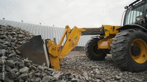 Tractor moves rubble to truck. Excavator-loader rakes rubble from pile at construction site and loads dump truck. Clearing site