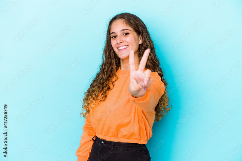 Young caucasian curly hair woman isolated joyful and carefree showing a peace symbol with fingers. Young caucasian curly hair woman isolated joyful and carefree showing a peace symbol with fingers.