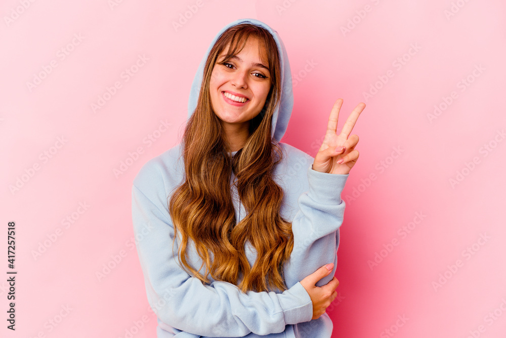 Young caucasian woman with hood isolated on yellow background showing number two with fingers. Young caucasian woman with hood isolated on yellow background showing number two with fingers.