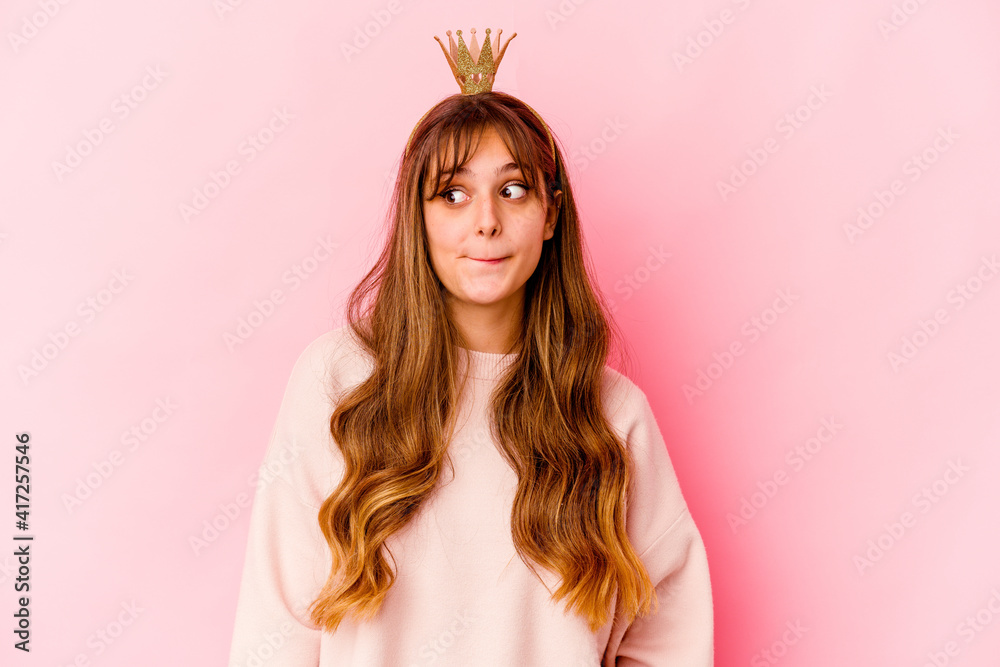 Young caucasian woman with princess crown isolated confused, feels doubtful and unsure.
