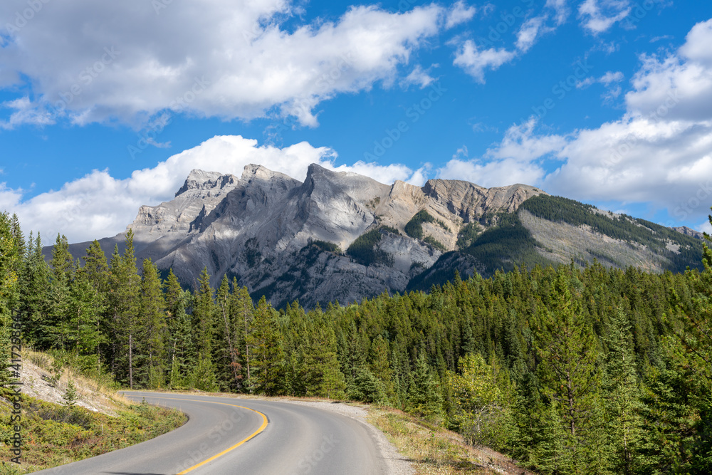 Mountain road in the forest in summer time. Lake Minnewanka scenic drive Loop. Banff National Park, Canadian Rockies, Alberta, Canada. Mountain road in the forest in summer time. Lake Minnewanka scenic drive Loop. Banff National Park, Canadian Rockies, Alberta, Canada.
