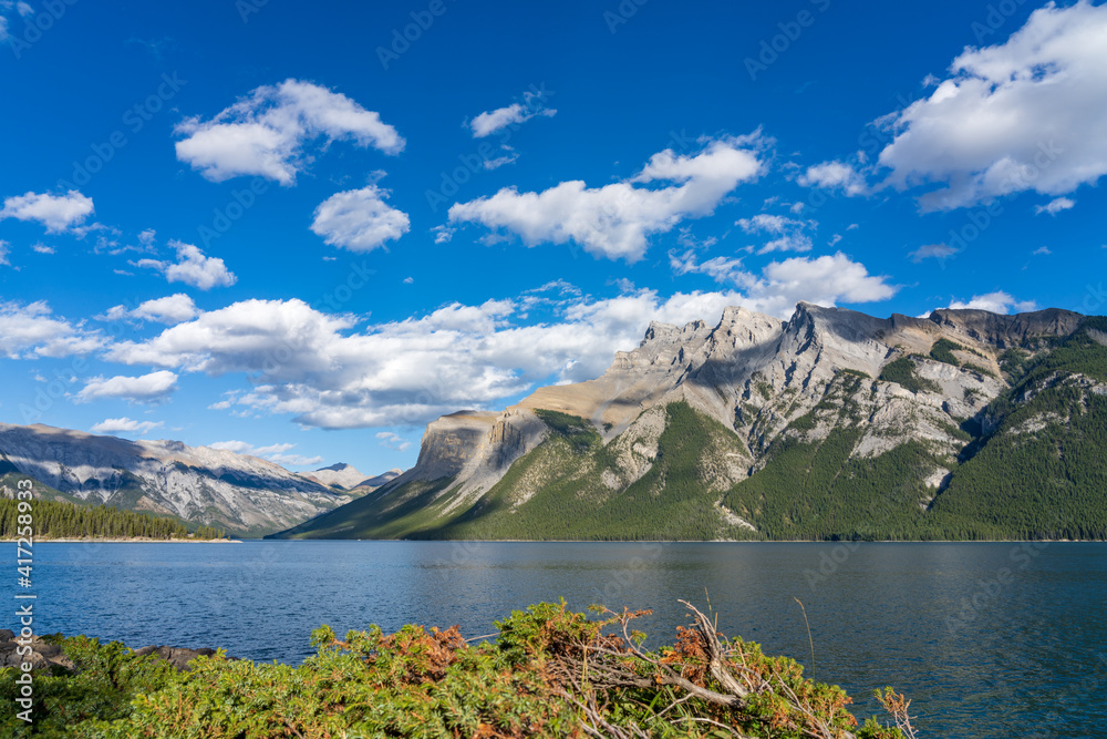 Lake Minnewanka beautiful landscape in summer day. Famous tourist attraction for leisure activities, boat cruise and mountain trail hiking in Banff National Park, Canadian Rockies.