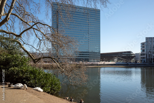 Outdoor tranquil scenery of pond and lake at Hofgarten park in Düsseldorf, Germany during winter and spring season and background of modern building. photo