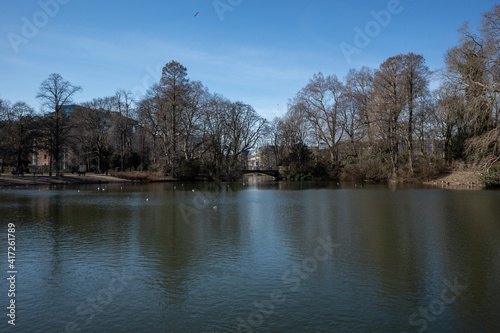 Outdoor tranquil scenery of pond and lake at Hofgarten park in Düsseldorf, Germany during winter and spring season.