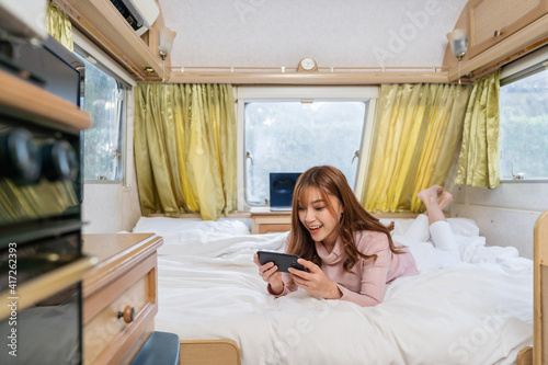 woman using smartphone on bed of a camper RV van motorhome