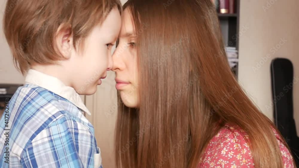 A young lovely woman consoles her little son bringing her face closer to his face and whispering something close-up A young lovely woman consoles her little son bringing her face closer to his face and whispering something close-up