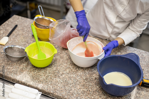 Confident kitchen staff female applying berry powder through sieve for decoration chocolate tart