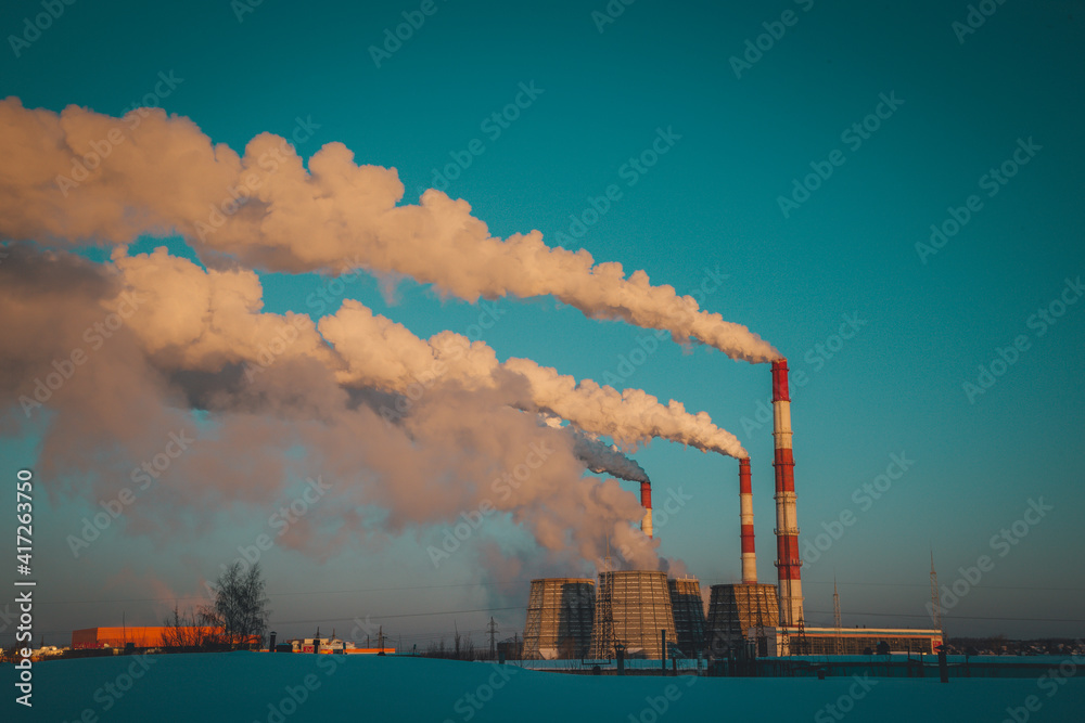 smoke from a working thermal power plant covers the blue sky in a frosty early morning