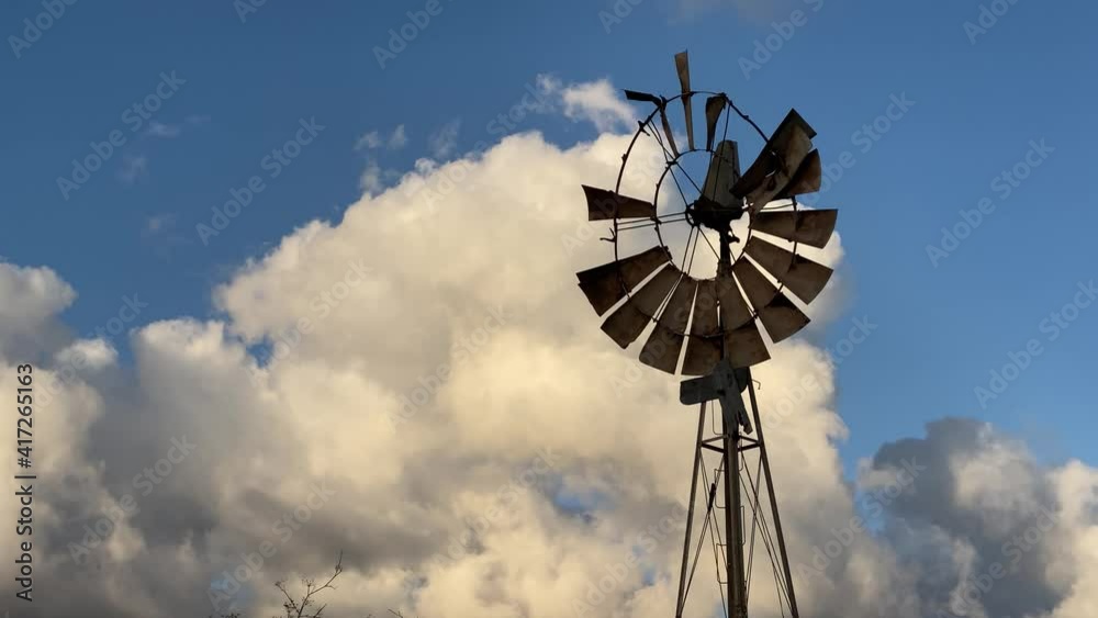 Old broken windmill against white clouds and blue sky- handheld