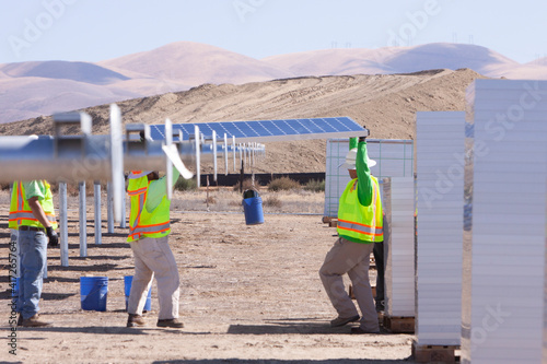 Two construction workers on construction site at solar farm installing solar panels