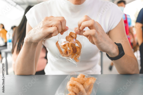 Woman in white t-shirt eats pork rind or pork crackling with Thai noodle.