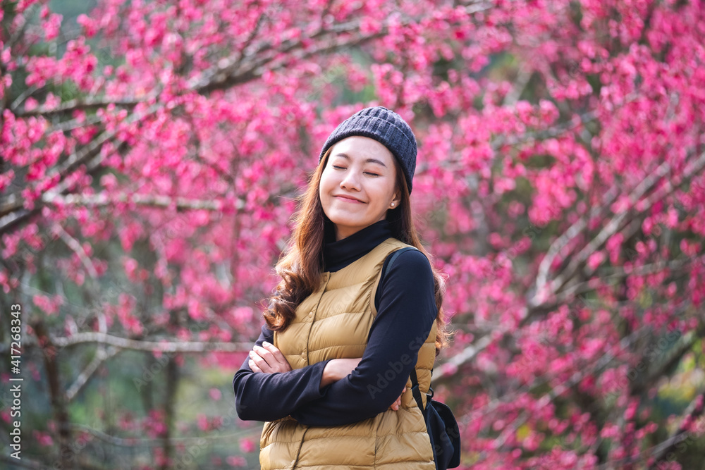 Portrait image of a beautiful young asian woman with pink cherry blossom flower in background Portrait image of a beautiful young asian woman with pink cherry blossom flower in background