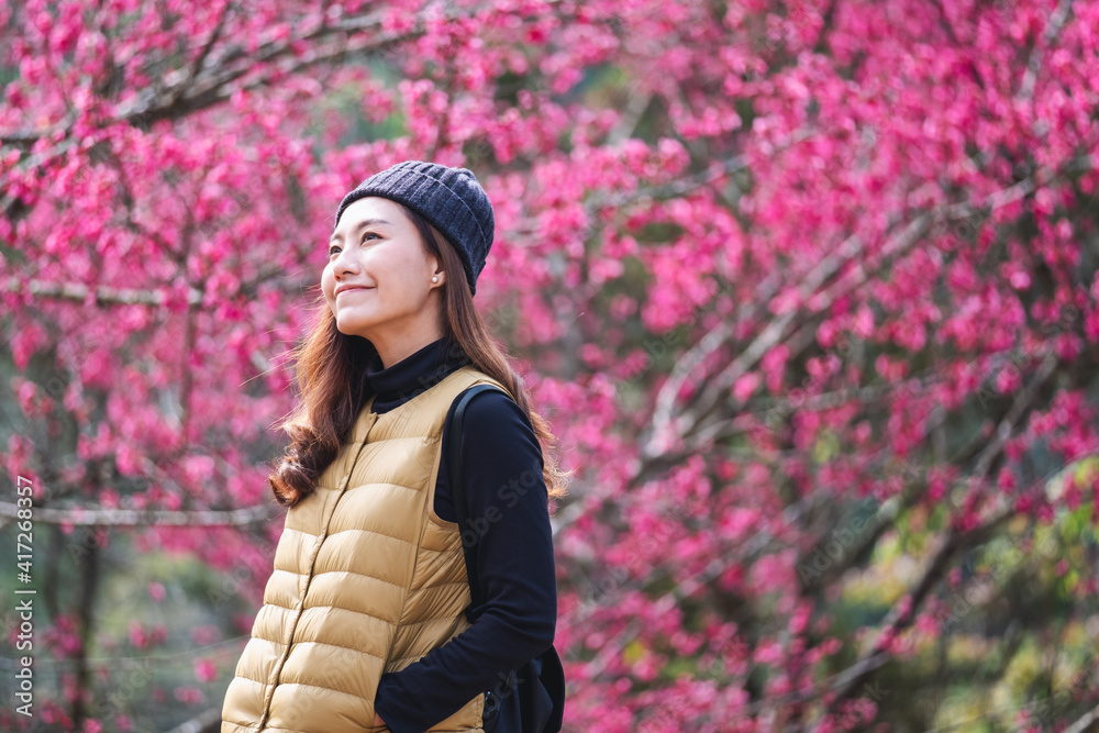 Portrait image of a beautiful young asian woman with pink cherry blossom flower in background Portrait image of a beautiful young asian woman with pink cherry blossom flower in background