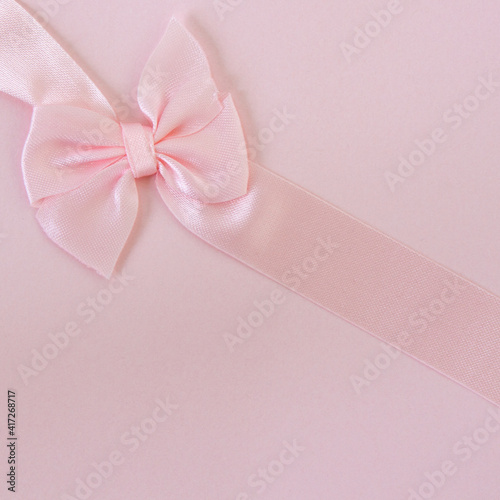Pink ribbon on pink background; Perfectly tied bow on diagonal ribbon