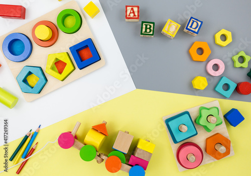 Wooden toys, blocks, a train on yellow gray background. Trendy cute baby first toys. Eco-friendly, plastic-free set of accessories for kids. Toys for kindergarten, preschool or daycare. Close up 