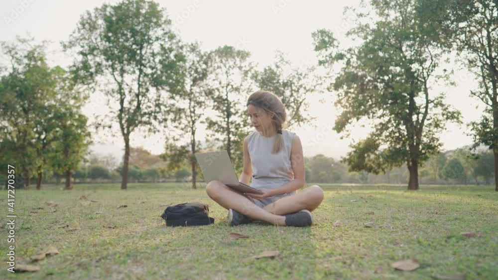 Young asian female working with laptop sitting down on green grass inside the park alone, relaxing remote work place, isolated alternative location for work, dyed blonde hair, technology and nature Young asian female working with laptop sitting down on green grass inside the park alone, relaxing remote work place, isolated alternative location for work, dyed blonde hair, technology and nature
