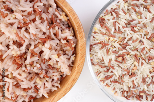 Cooked and raw mixed low glycaemic index healthy rice grain basmati millet buckwheat red rice in wooden and glass bowl on white background photo