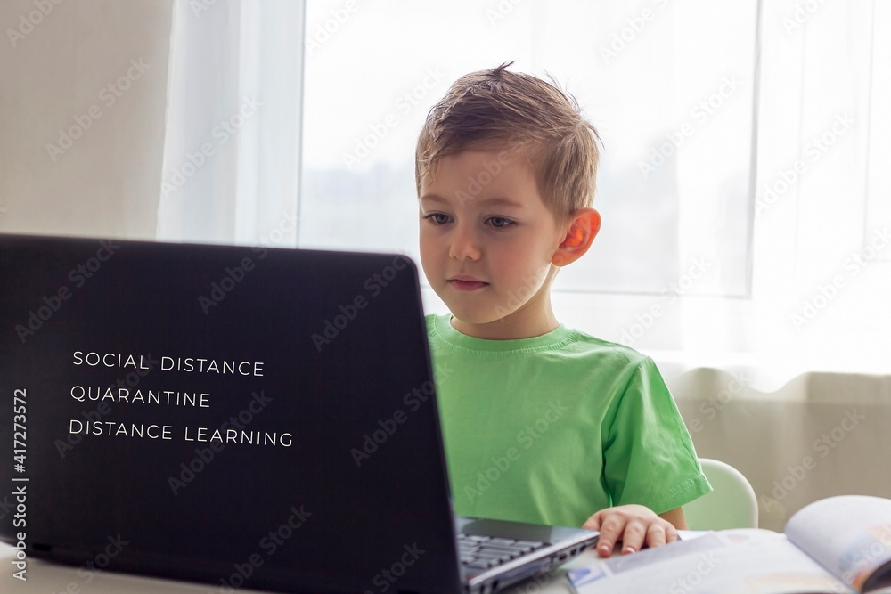 Distance learning, online education. Social distance and self-isolation during quarantine. Preschooler or schoolboy studying at home with notebook and doing homework. Selective focus