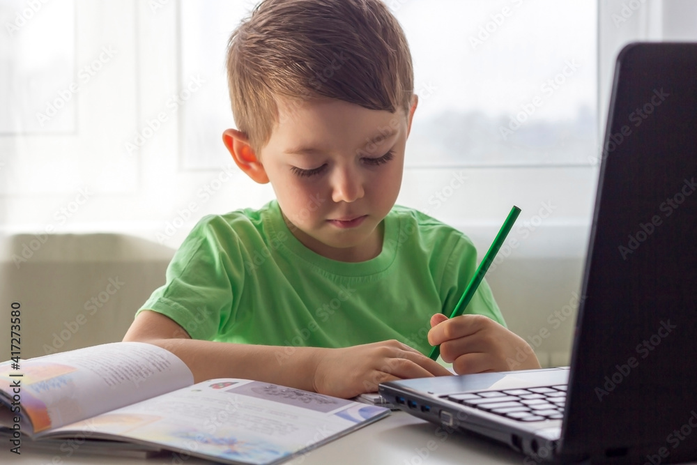 Distance learning, online education. Social distance and self-isolation during quarantine. Preschooler or schoolboy studying at home with notebook and doing homework for development school. Distance learning, online education. Social distance and self-isolation during quarantine. Preschooler or schoolboy studying at home with notebook and doing homework for development school.